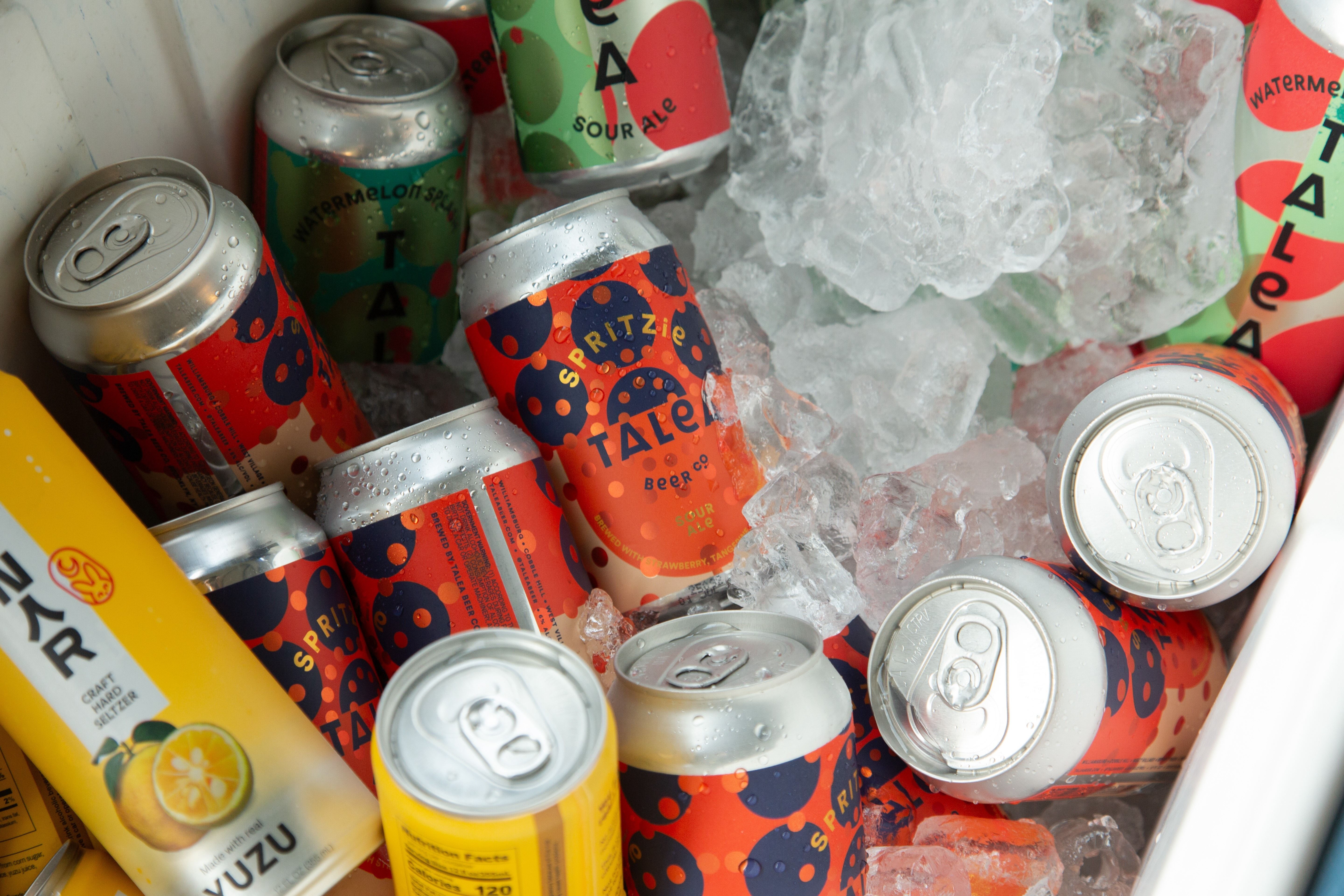 Talea Beer cans of various colors and flavors in a cooler with ice.