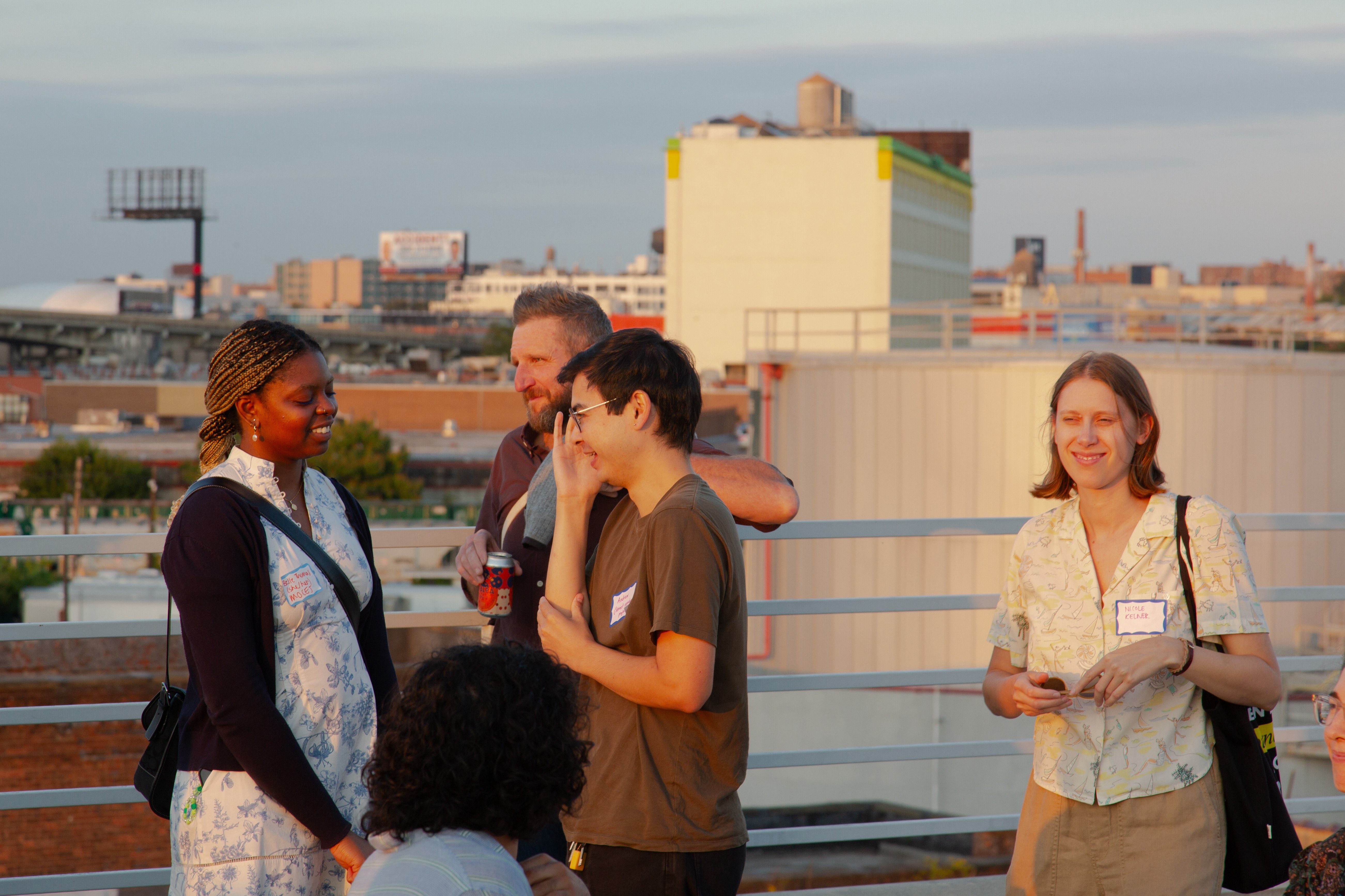 People smiling in conversation with sunset-lit city skyline in the background.